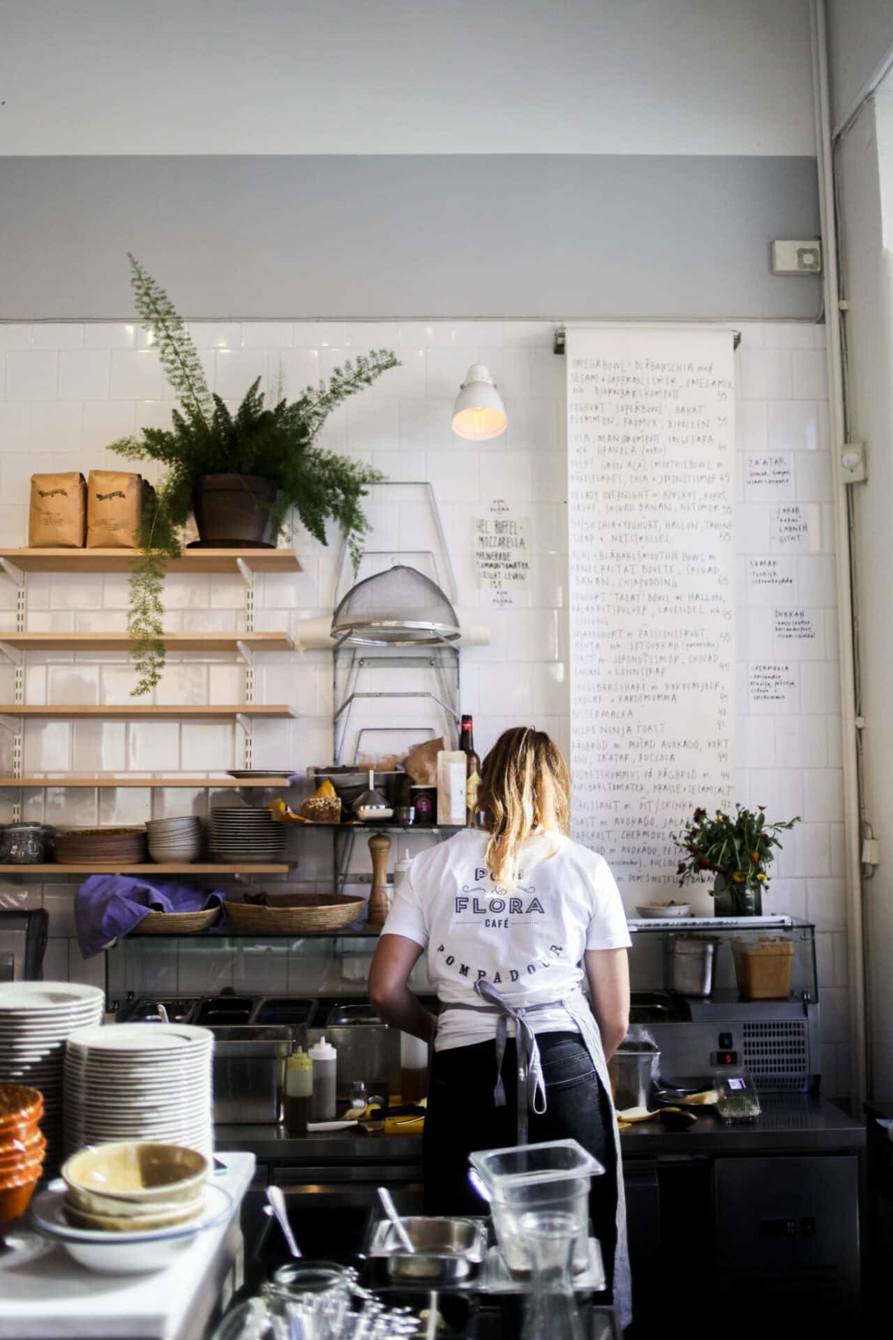 A woman behind the counter prepares coffee for customers.