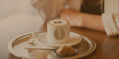 A coffee cup on the table with a person in the background