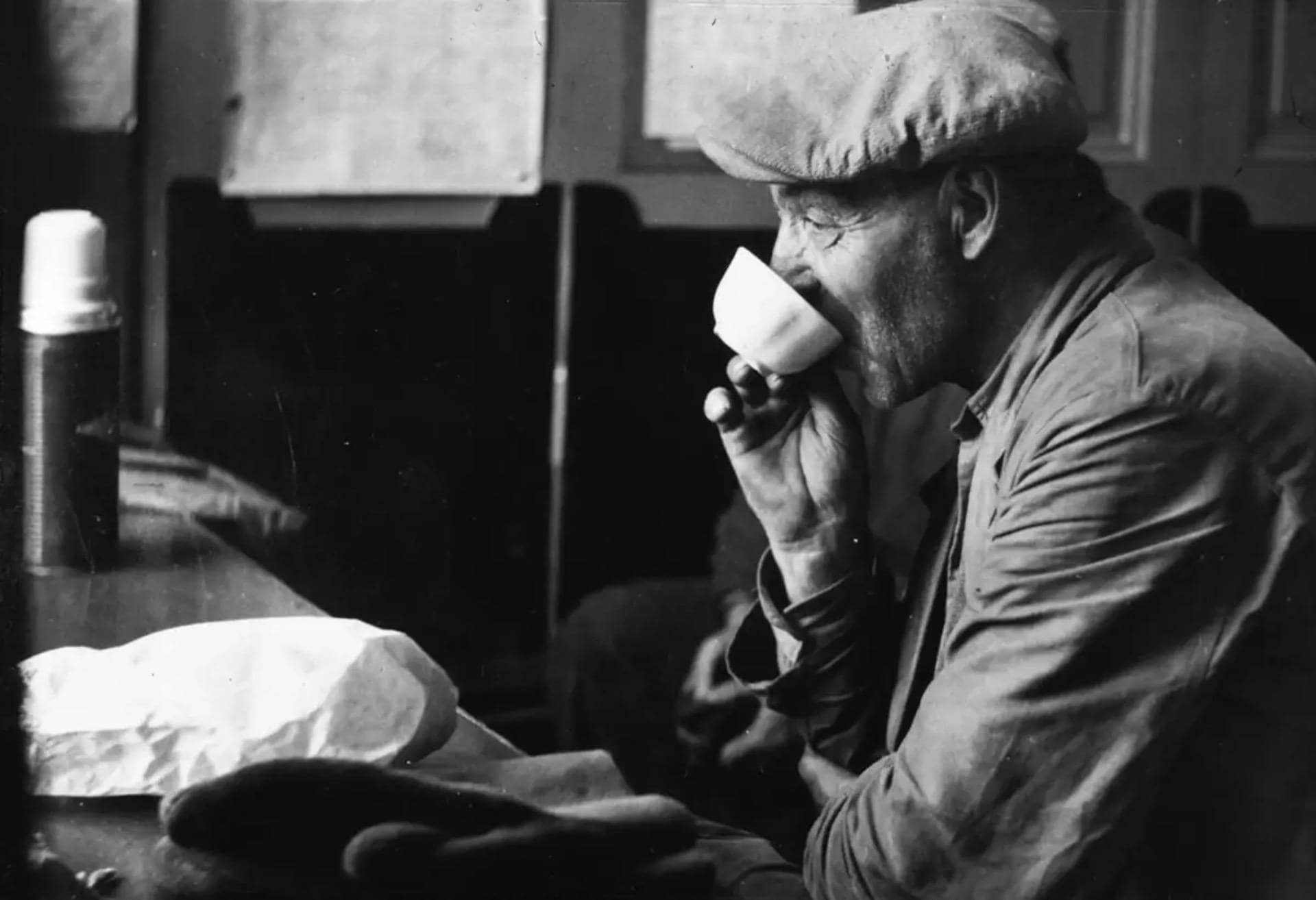 Old black and white picture of a man drinking coffee.