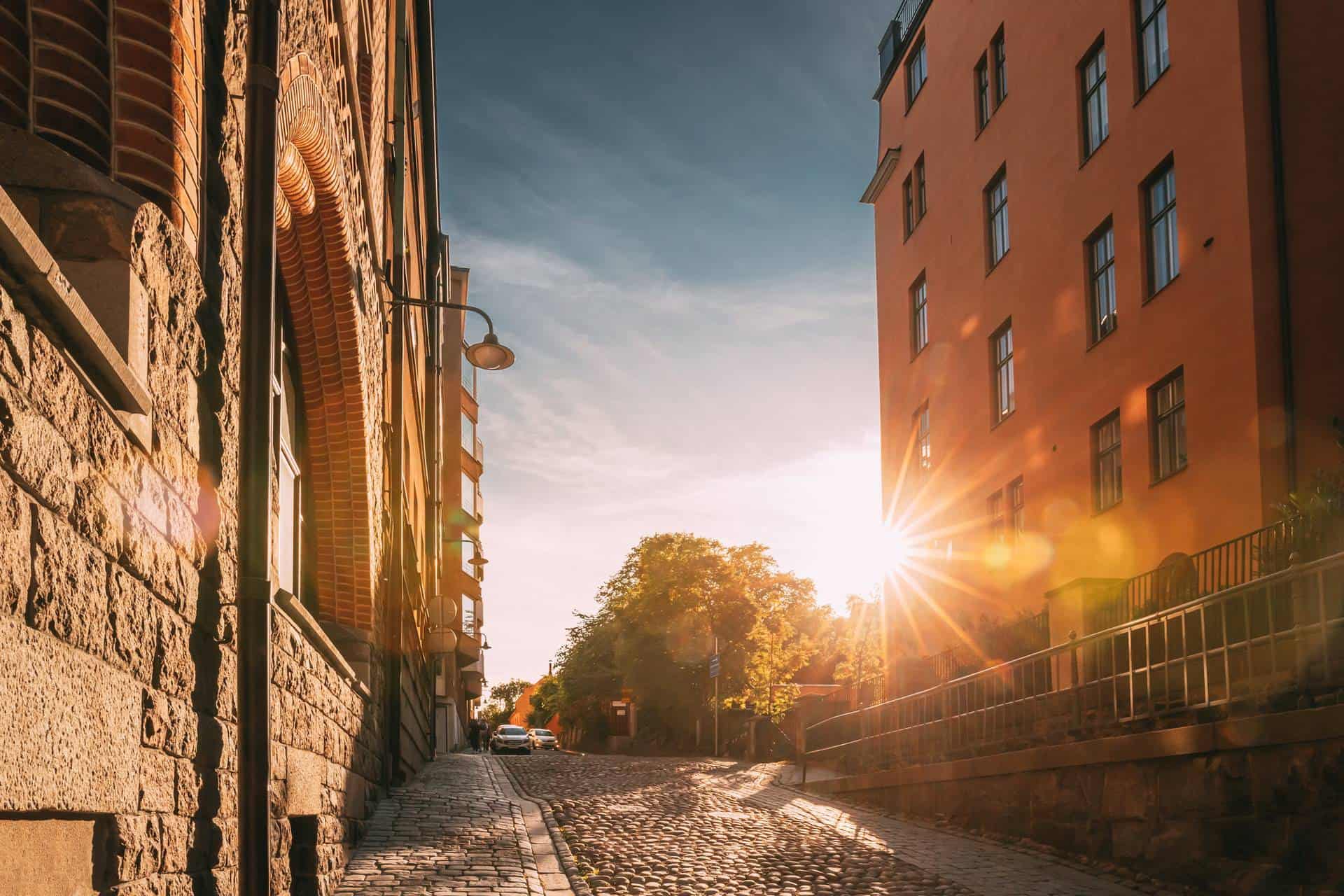 Sunshine during sunset above Stockholm street with multi storey house in sunny summer evening.